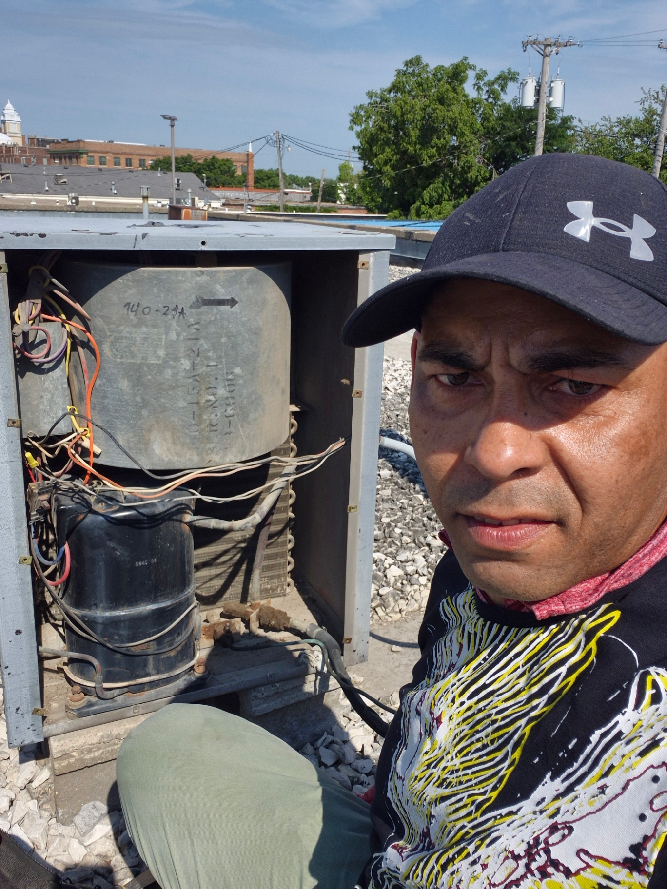HVAC technician next to an open commercial rooftop unit during a refrigerant leak diagnostic in Fort Dodge, Iowa