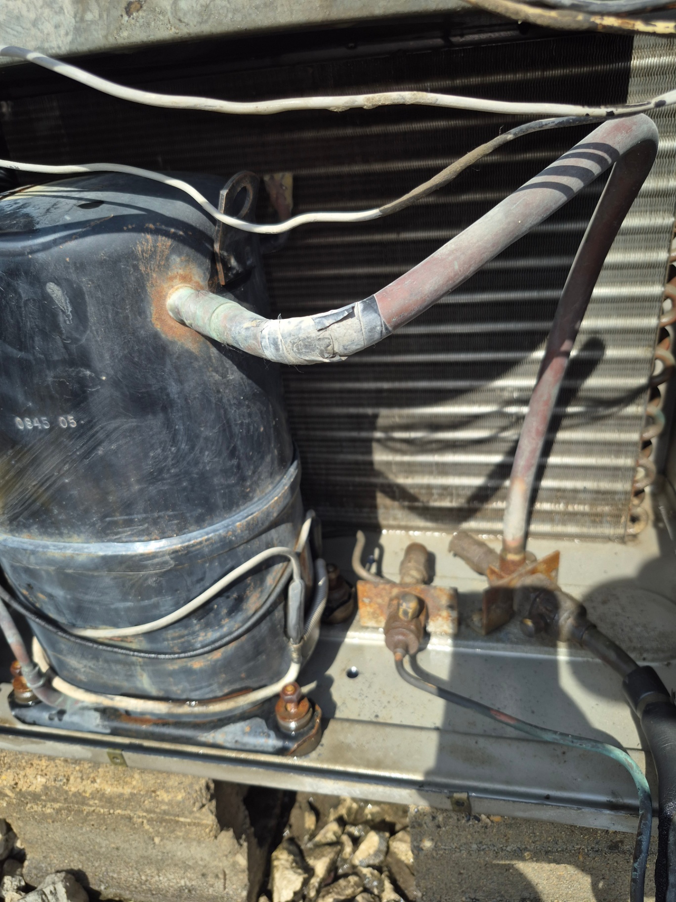 Close-up of a commercial HVAC compressor and refrigerant suction and discharge lines showing wear and leak point