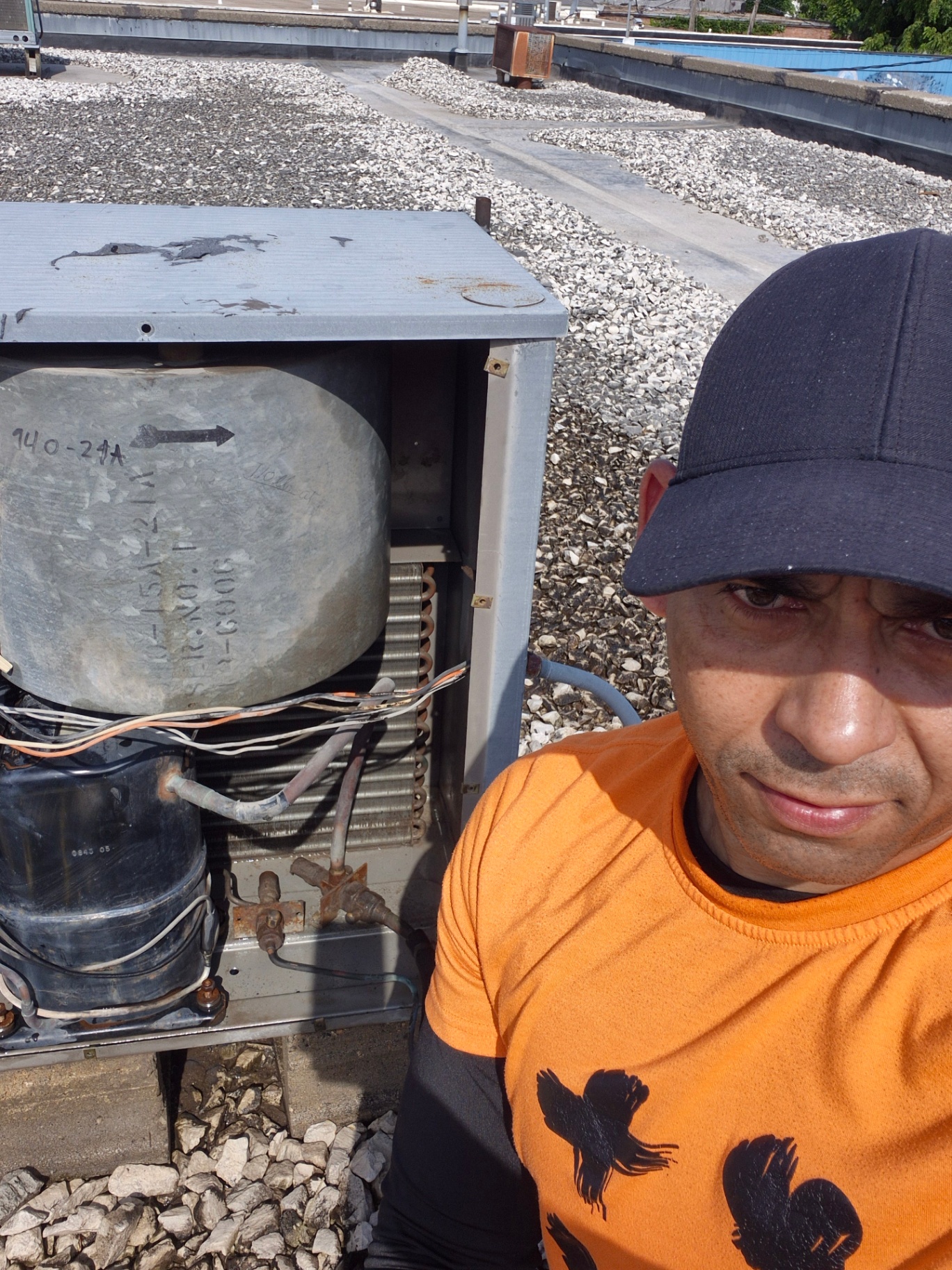 HVAC technician standing next to a commercial rooftop AC unit before starting the refrigerant leak repair