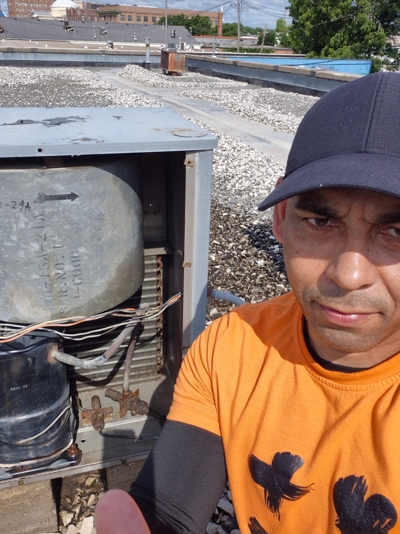 Inside view of a commercial rooftop HVAC unit showing compressor, coil and refrigerant lines during service