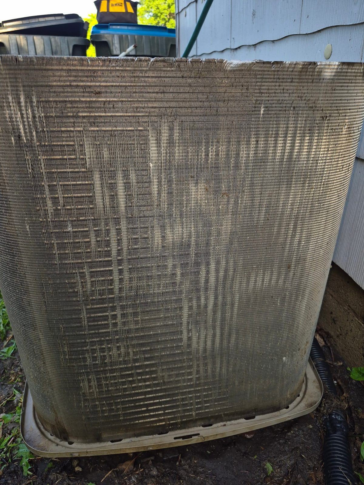 Full outdoor condenser coil covered in a heavy layer of dirt and cottonwood before service